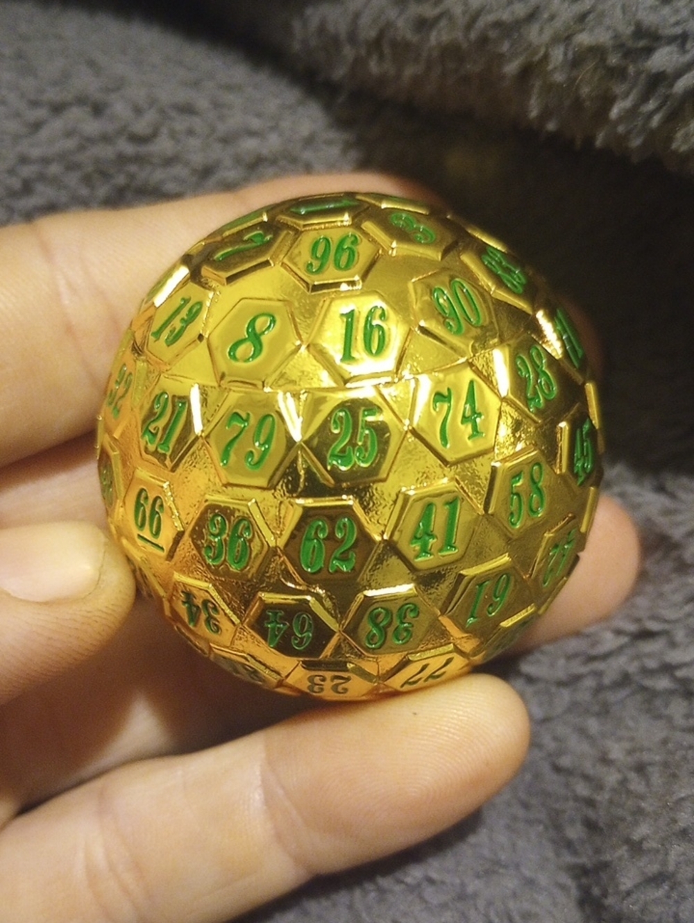 This is a 45mm gold metal 100-sided die (D100) featuring distinctive green paint